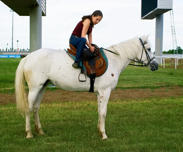 Fille monter un cheval sur un hippodrome — Photo