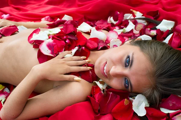微笑女孩在玫瑰的花瓣 — 图库照片