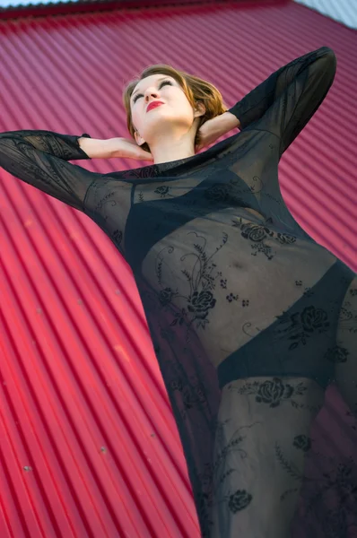 Девушка в черном платье против красной стены — стоковое фото