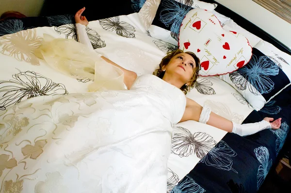 Sposa in un abito da sposa si trova su un letto — Foto Stock