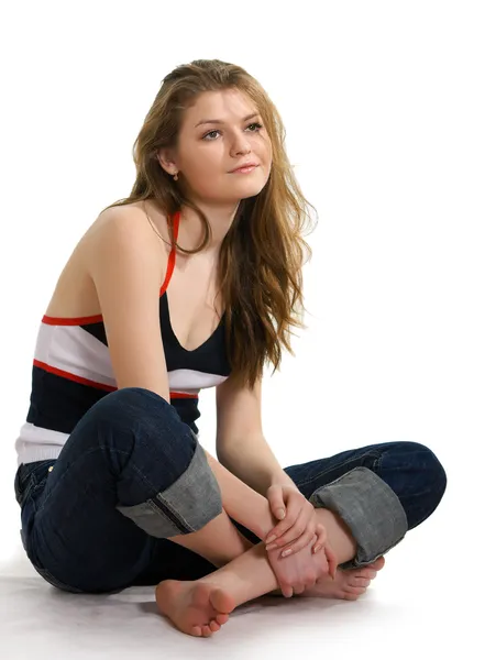 Girl in jeans sits on a white — Stock Photo, Image