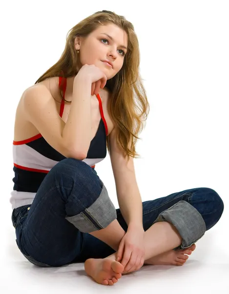 Dívka v džíny sedí na bílé — Stock fotografie