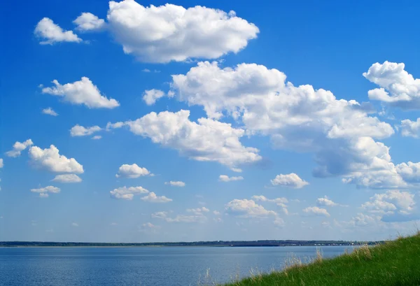 Lake, blauwe bewolkte hemel en groen gras — Stockfoto