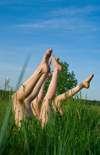 Feet of girls laying in a grass — Stock Photo, Image
