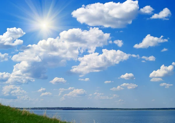 Jezioro, zachmurzone niebo niebieskie i trawa zielona — Zdjęcie stockowe