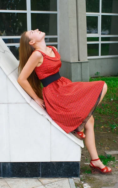 Κορίτσι με κόκκινο φόρεμα ενάντια σε κτίριο — Φωτογραφία Αρχείου