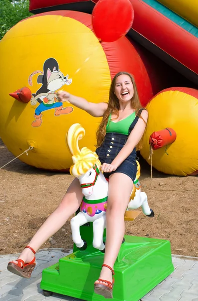 Śmiejąca się dziewczyna okrakiem na koniu zabawka — Zdjęcie stockowe