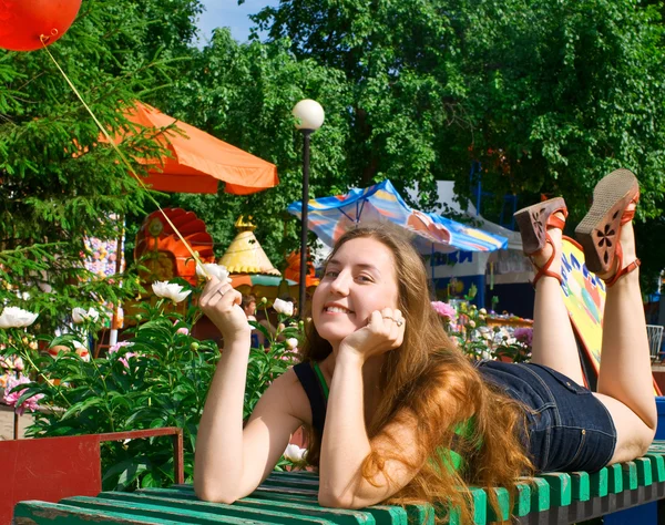 Αστείο κορίτσι βάζει σε ένα παγκάκι στο πάρκο — Φωτογραφία Αρχείου