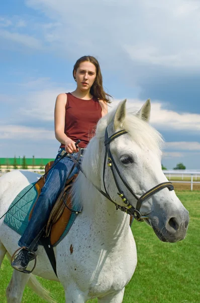 Meisje schrijlings op een paard tegen blauwe hemel — Stockfoto