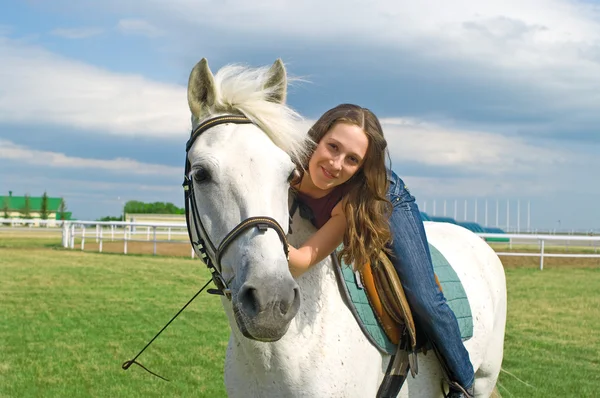 Улыбающаяся девушка обнимает белую лошадь — стоковое фото