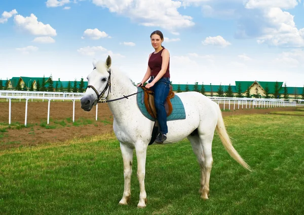 Lachende jong meisje schrijlings op een paard — Stockfoto