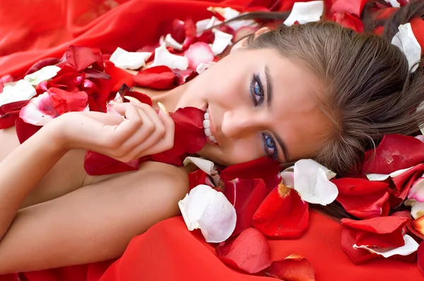 Красивая девушка в лепестках роз — стоковое фото