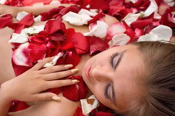 Спящая девушка в лепестках роз — стоковое фото