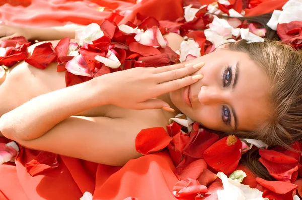 Молодая девушка в лепестках роз — стоковое фото