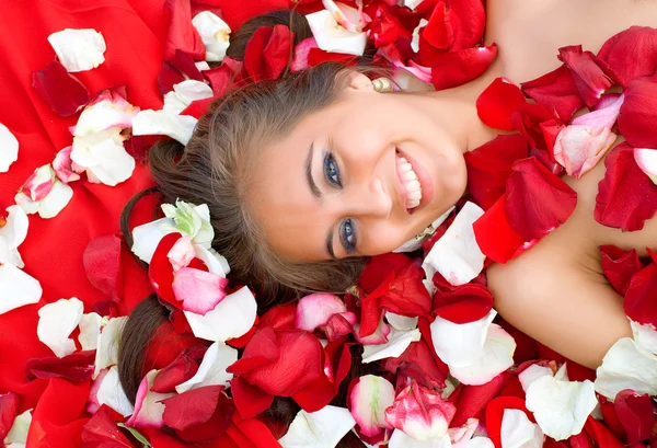 Vacker ung flicka i rosenblad — Stockfoto
