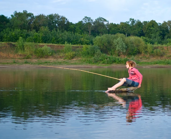 Menina-pescador senta-se em um log — Fotografia de Stock