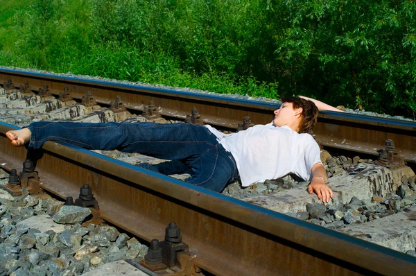 Jovem deitado em uma ferrovia — Fotografia de Stock