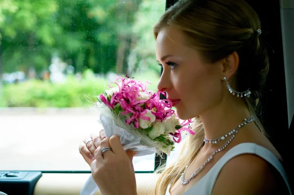Bride with flowers in car — Stock Photo, Image