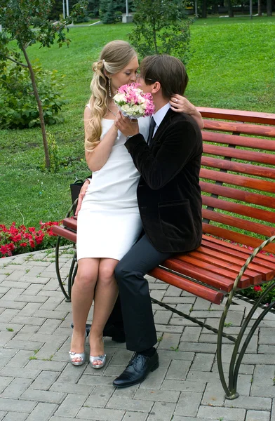 Bride and groom sit on the bench — Stock Photo, Image