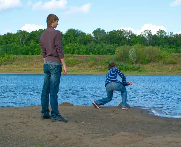Junge Männer werfen Stein in den Fluss — Stockfoto