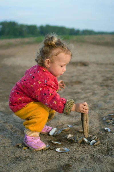 Girl plays with cockleshells — Stock Photo, Image