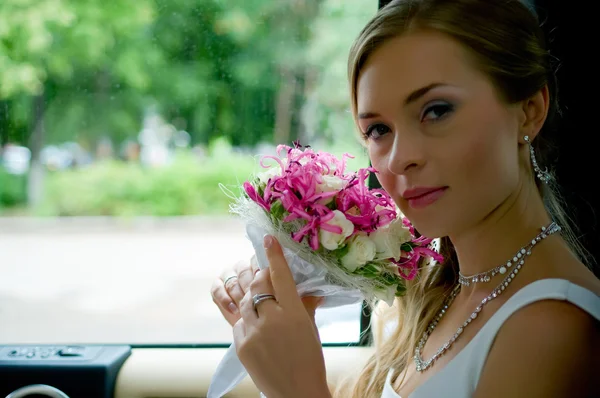 Bride with flowers in car — Stock Photo, Image