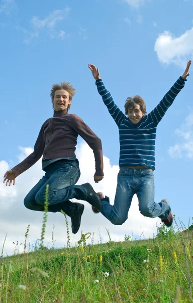 Мужчины прыгают против летнего пейзажа — стоковое фото