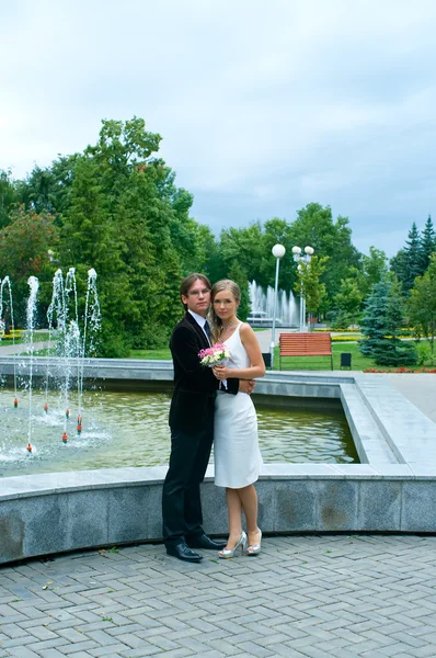 Bride and groom against urban fountain — Stock Photo, Image