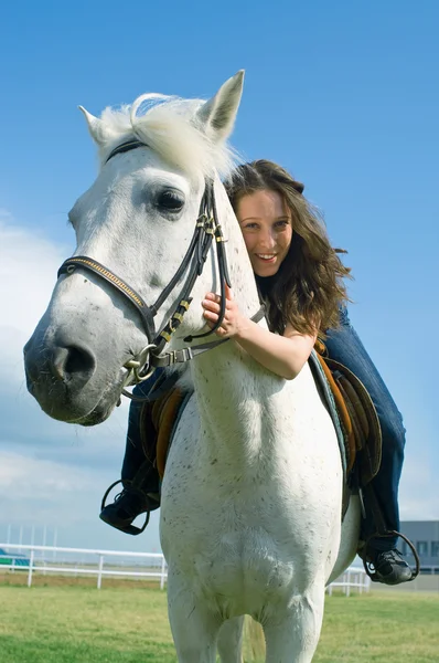 Sorrindo menina abraça um cavalo branco — Fotografia de Stock