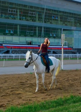 Girl astride a horse on a hippodrome clipart