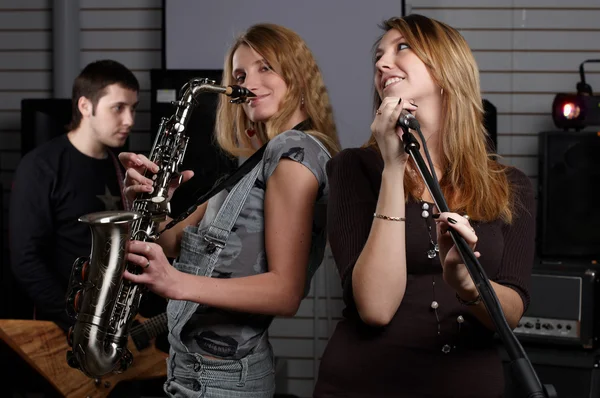 Iki genç kadın şarkı imzalamak ve saxo üzerinde oynamak — Stok fotoğraf