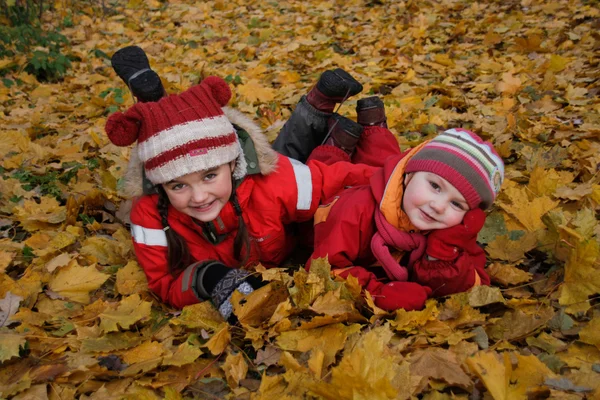 Duas meninas felizes deitado em folhas de outono Imagens Royalty-Free