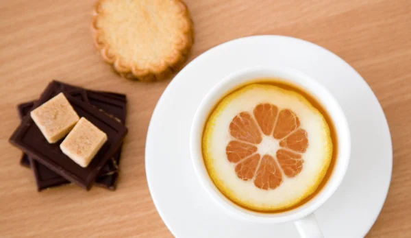 Kuppi mustaa teetä sitruunalla, sokerilla, kekseillä ja suklaalla — kuvapankkivalokuva