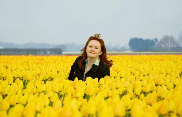 Beautiful woman in yellow tulips — Stok fotoğraf