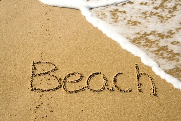 Слово пляж написано на песке — стоковое фото