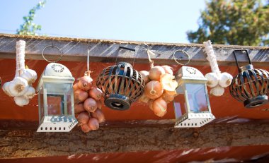 Rustic home decoration - lanterns and hanging dried onion and garlic clipart