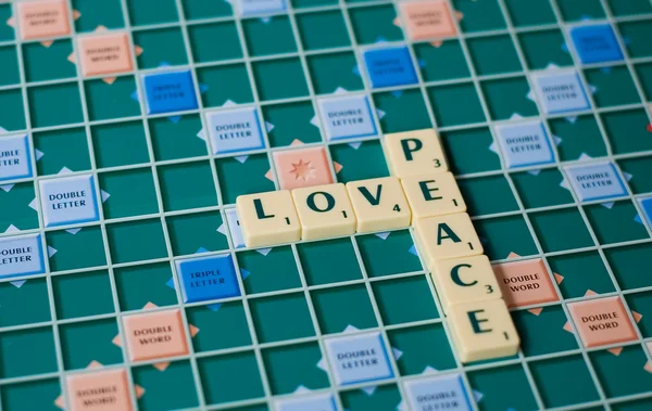 Buchstaben eines Brettspiels bilden die Wörter Liebe und Frieden — Stockfoto