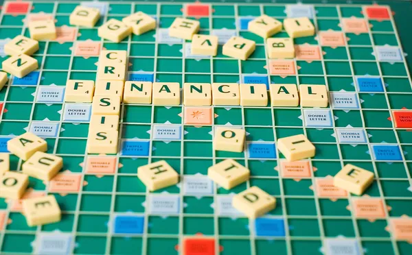Письма из настольной игры, формирующие слова Финансовый кризис — стоковое фото