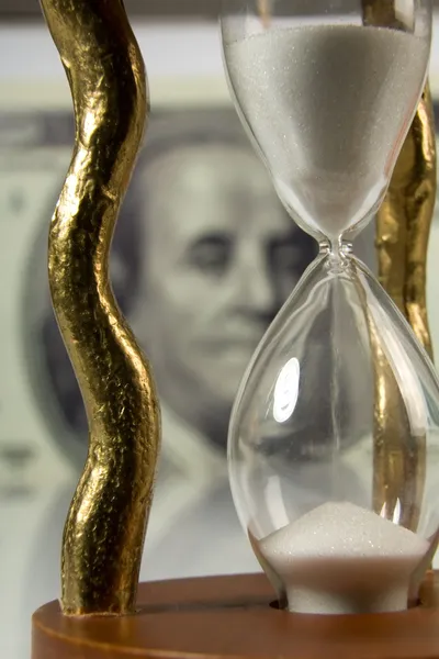 Hourglass on big dollar background — Stock Photo, Image