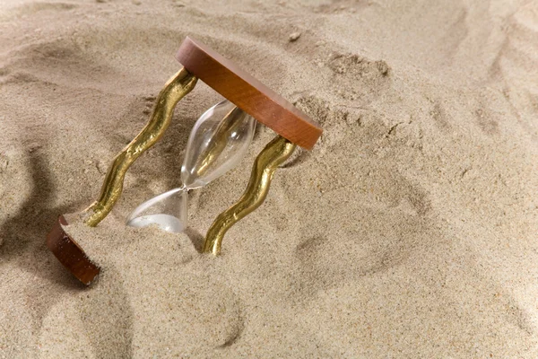 Песочные часы на песчаной поверхности — стоковое фото