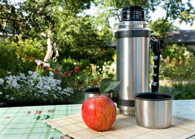 Thermos and apple on background clipart
