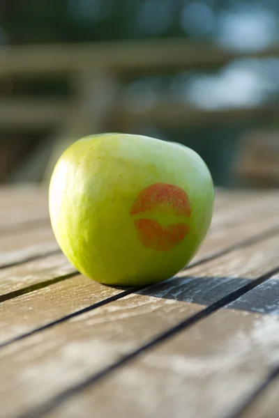 Apple with kiss on wood board — Stock Photo, Image