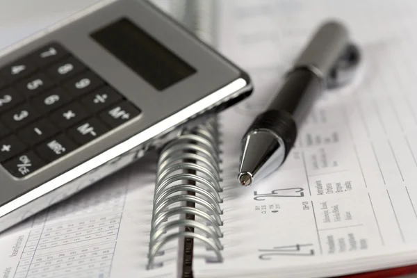 Ручка и калькулятор на блокноте — стоковое фото