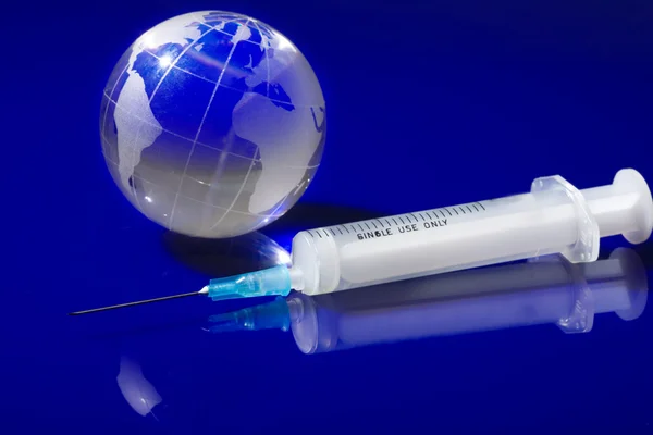 Glass globe with a syringe — Stock Photo, Image