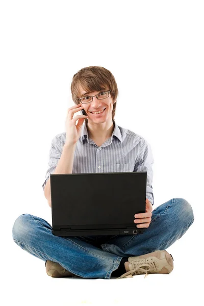 Jonge man met laptop en mobiele telefoon. Stockafbeelding