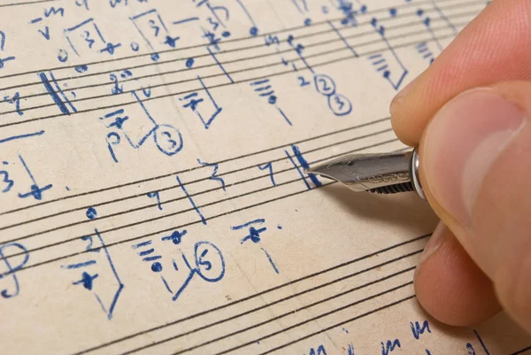 Hand met pen en muziek blad — Stockfoto