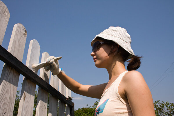 Beautiful girl colours a wooden fence
