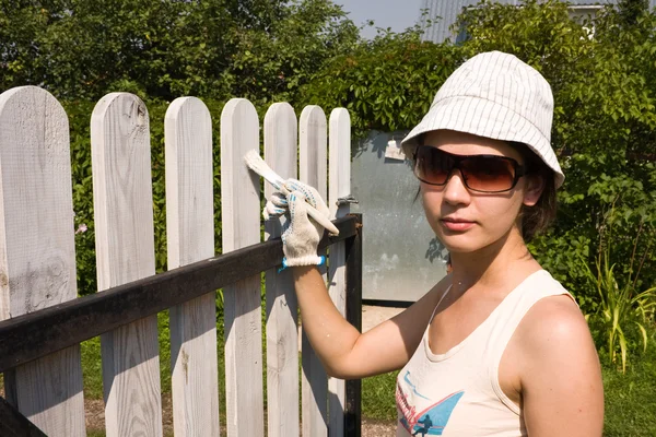 Hermosa chica colorea una valla de madera — Foto de Stock