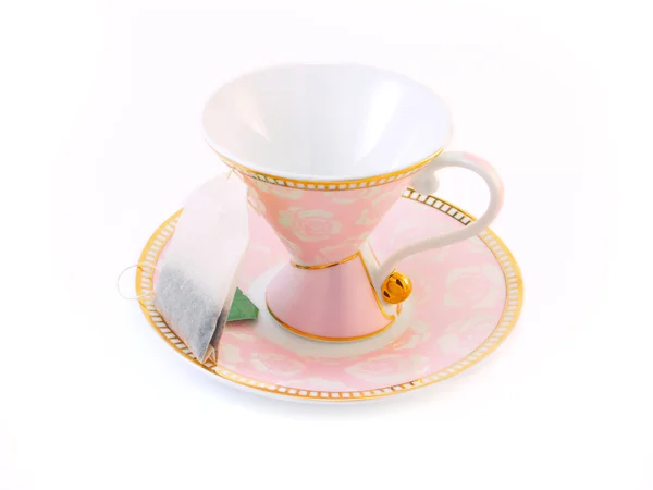 Tazza di tè rosa su un piattino e una bustina di tè — Foto Stock