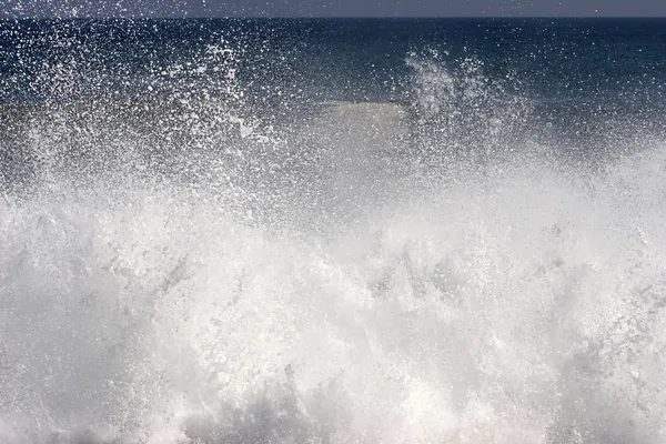 Spray and foam from wave hitting the shore — Stock Photo, Image